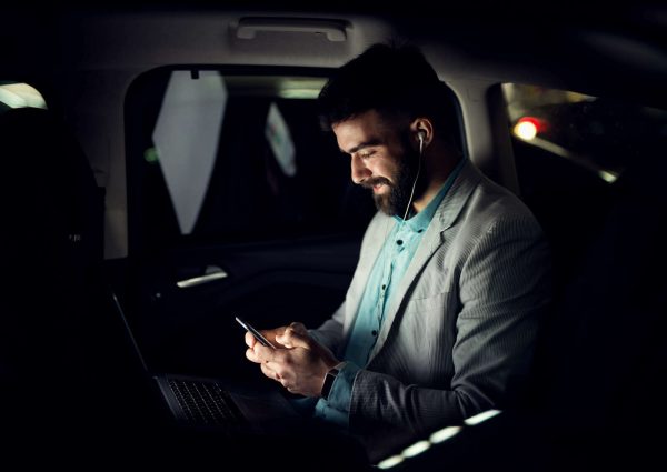businessman typing on mobile phone in the car.